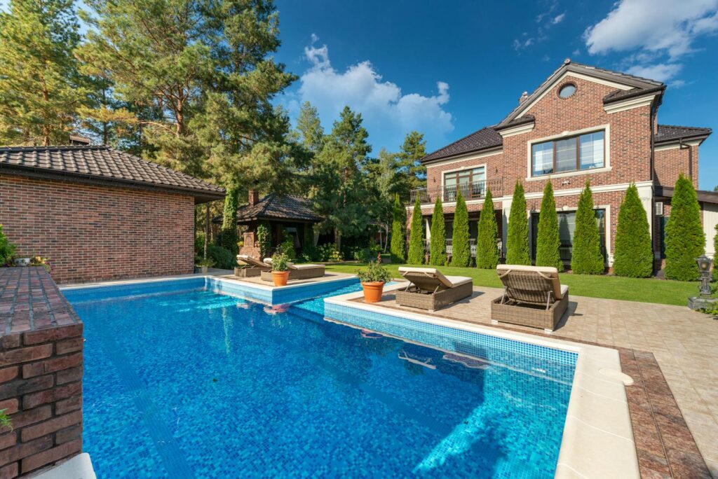 Beautiful brick residence with swimming pool, surrounded by trees and greenery.